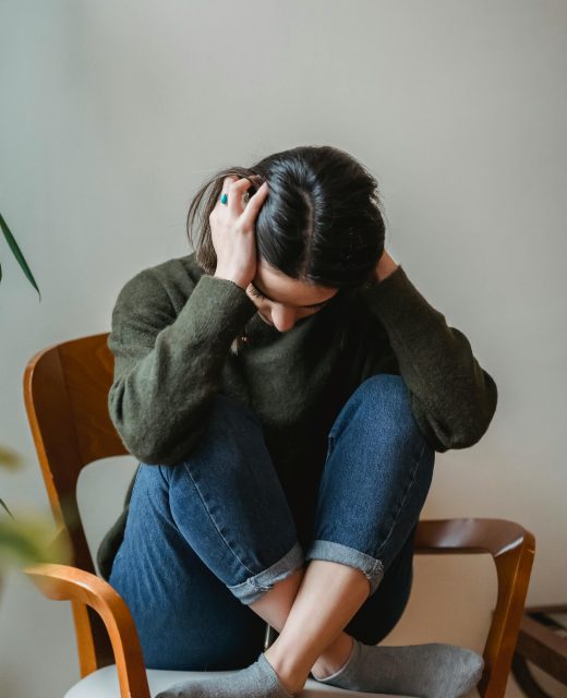 Woman covering ears sitting on chair stressed out