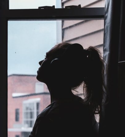 silhouette photo of a woman looking through window